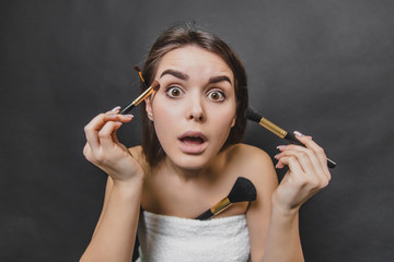 Obraz premium Close up portrait of gorgeous girl with four makeup brushes. Frightened facial expression.