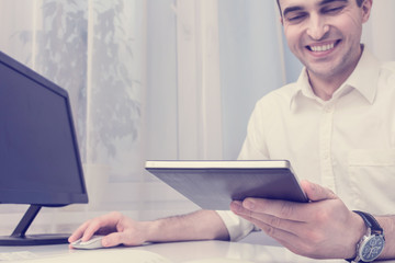 Businessman working in the office, uses tablet, front view, toned