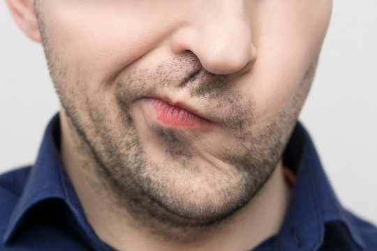Grimace of irritation or discontent on the face of a bearded man, close up, cropped image