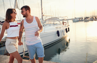 Man and woman in love holding hand enjoying in romantic walking on the dock at sunset..