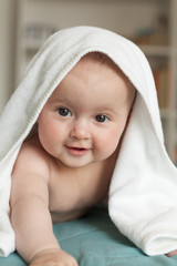 Little baby smiling, laughing.Cute baby lying on her tummy over a white towel.
