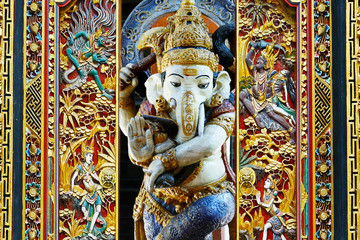Obraz premium statue of ganesh …god of prosperity and success with carved door in balinese temple 