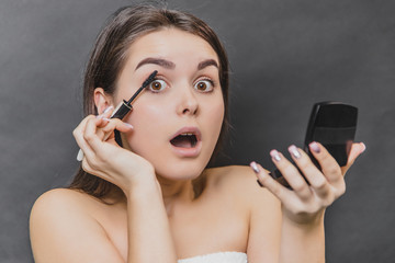 Beautiful young girl on a black background close up. The use of carcasses for eyelashes, the beauty of the face, the clean skin that looks into the camera, make up the concept.