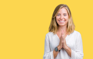 Beautiful young elegant woman over isolated background praying with hands together asking for forgiveness smiling confident.