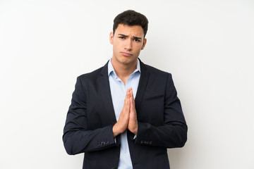 Handsome man over isolated white wall pleading