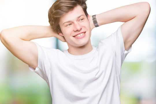 Young handsome man wearing casual white t-shirt over isolated background Relaxing and stretching with arms and hands behind head and neck, smiling happy
