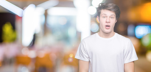 Young handsome man wearing casual white t-shirt over isolated background afraid and shocked with...