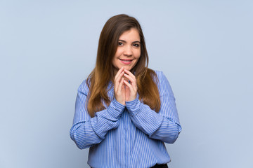 Young girl over isolated blue wall scheming something