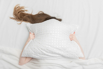 Girl sleeping in the bedroom, woman covering with pillow, girl does not want to get up so early, copy space