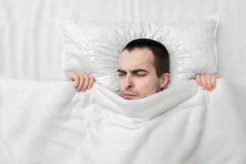 Guy sleeping in the bedroom, guy's having a nightmare, white blanket, top view