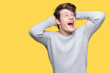 Young handsome man wearing winter sweater over isolated background Crazy and scared with hands on head, afraid and surprised of shock with open mouth