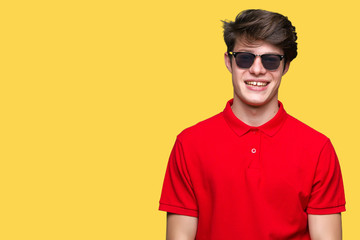 Young handsome man wearing sunglasses over isolated background with a happy and cool smile on face. Lucky person.