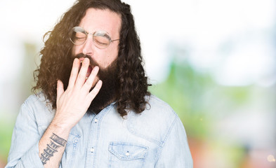 Fototapeta na wymiar Young hipster man with long hair and beard wearing glasses bored yawning tired covering mouth with hand. Restless and sleepiness.