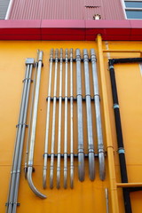 pattern of many pipes on yellow wall at outdoor of factory .