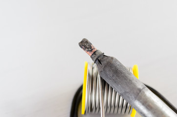 solder wire and soldering iron with wooden handle on gray background