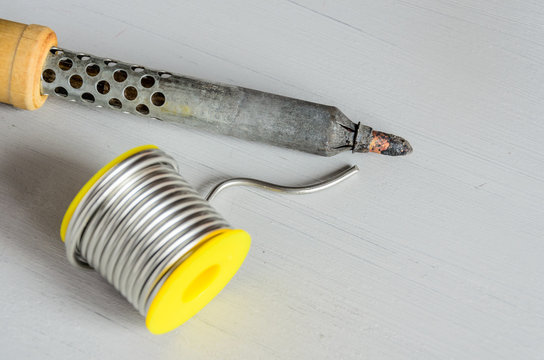 solder wire and soldering iron with wooden handle on gray background
