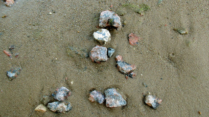 The photo shows a small number of stones on the sand near the river