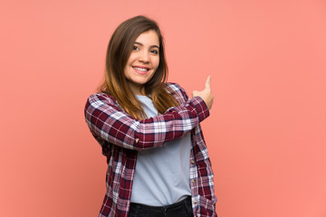 Young girl over pink wall pointing back