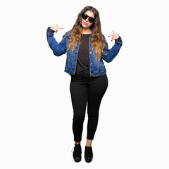 Young beautiful woman wearing sunglasses looking confident with smile on face, pointing oneself with fingers proud and happy.