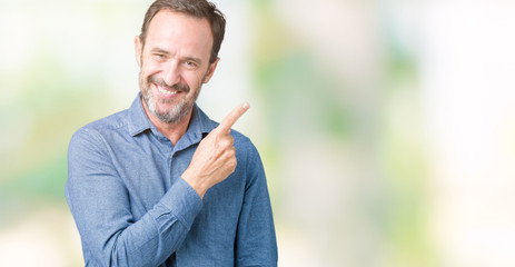 Handsome middle age elegant senior man over isolated background cheerful with a smile of face pointing with hand and finger up to the side with happy and natural expression on face
