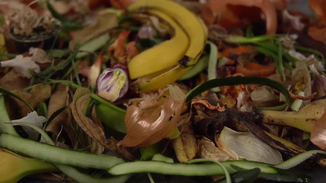 Tracking shot close up of food debris from onions, bananas, cucumbers, carrots, apples, potatoes, herbs. Organic garbage collection for compost pit. Concept of zero waste and caring for environment.