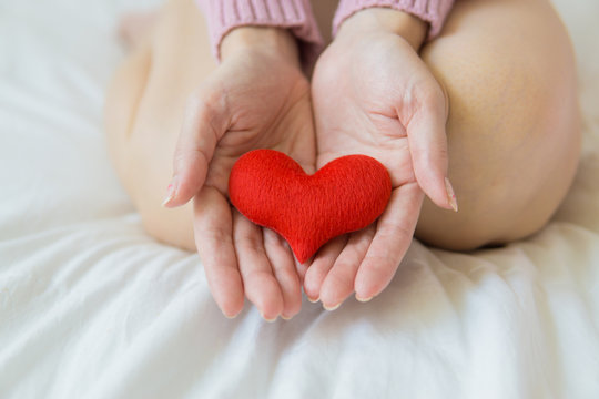 Asian woman holding a red heart in her hands.
