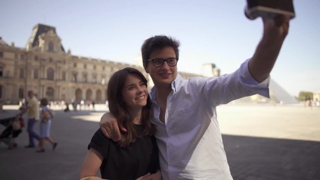 A beautiful young woman with dark hair in a black t-shirt and young cheerful man in a shirt take a selfie. Slow motion portrait shot.