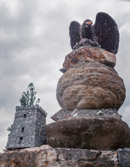 Eagle sculpture on a rock; large, gray building with towers at the top of the perimeter