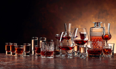 Set of strong alcoholic beverages in glasses on a brown background.