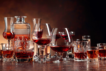 Set of strong alcoholic beverages in glasses on a brown background.