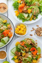 Healthy summer fresh salad with mango, avocado, lime and tofu with sweet peanut butter dressing on white wooden table