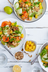 Healthy summer fresh salad with mango, avocado, lime and tofu with sweet peanut butter dressing on white wooden table