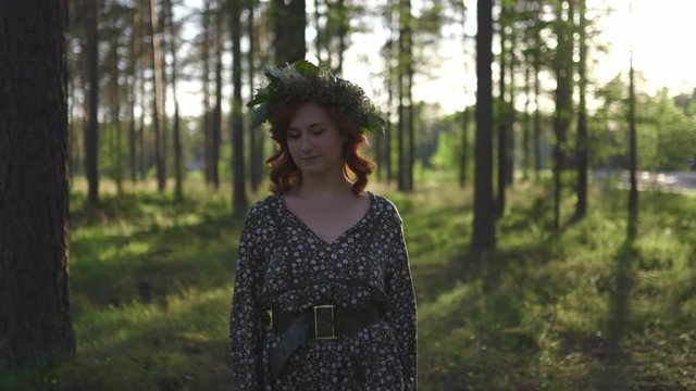 Walking: Redhead young woman in a Wreath during traditional latvian Ligo midsummer day - Caucasian white girl wearing a dotted summer dress with a belt in sunny sunset