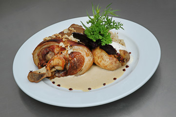Roasted pork knuckle with stewed cabbage and vegetables on plate, on gray background