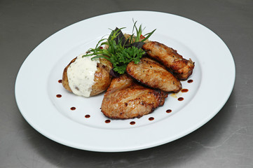 Chicken wings, stuffed potatoes, mint, dill, on a plate on a gray background