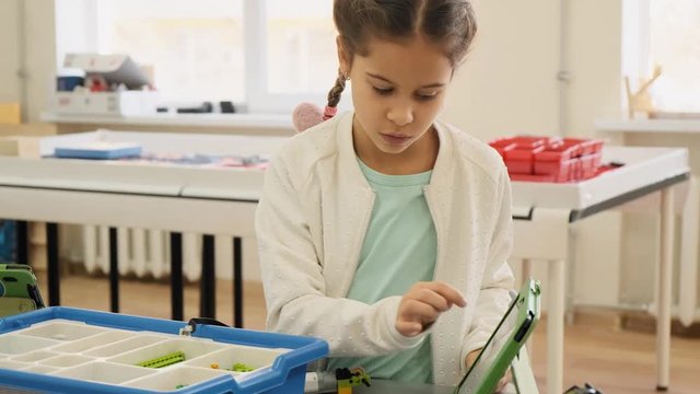 Little girl shows on her ipad the nessesary plastic construction for the educational lesson slow motion