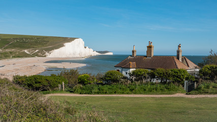 Fototapeta na wymiar The Seven Sisters white chalk cliffs viewed over traditional old fisherman's cottages on the Sussex coast of England near Seaford and Cuckmere Haven.