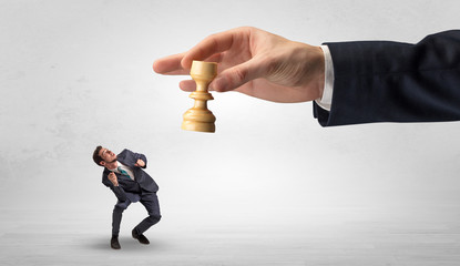 Big hand holding chessman and down little afraid businessman concept in a light space
