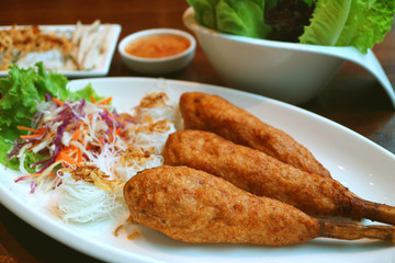 Plate of deep fried Vietnamese minced prawn wrapped around sugar cane with rice vermicelli or Chao Tom 