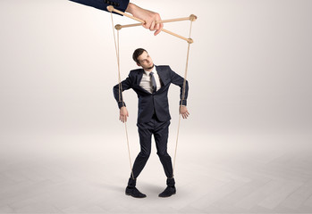 Puppet businessman in an empty room leaded by a huge hand
