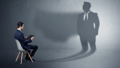 Fototapeta premium Humble businessman staying and offering stuffs to a huge angry bull shadow 