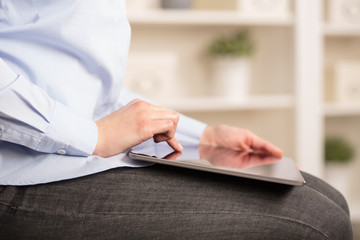 Business woman below chest using tablet in a homey environment
