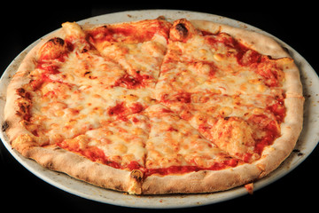 closeup whole sliced four cheese pizza on black background