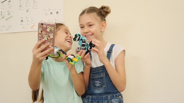 Happy kids have fun and laugh while doing selfie with robot cars at the class slow motion
