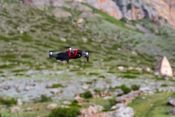 Modern dark and red drone in the air in mountains close