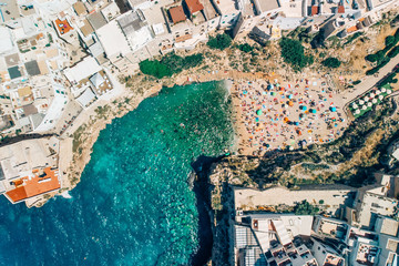 Fototapeta na wymiar Many tourists relax on beach in Poliano a Mare summer days, drone shot
