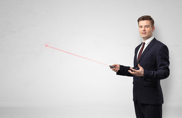 Young businessman with laser pointer and copyspace white wall
