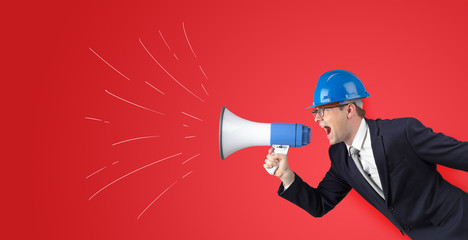 Fototapeta premium Young architect constructor yelling with megaphone and copyspace 