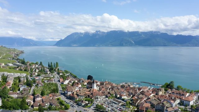Aerial slow orbiting movement above Lutry village in Lavaux vineyard. Lake Leman and the Alps in background, Switzerland