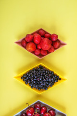 Cherries, strawberries, blue berries on yellow background. Colorful concept. Natural organic vegan healthy fresh food.